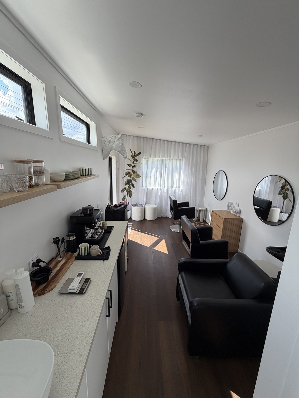 Light-filled salon interior with timber cabinetry and black chairs